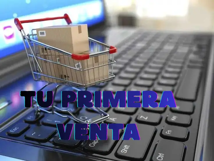 Carrito de compras con paquete sobre un teclado de computadora, representando una primera venta en una tienda online.